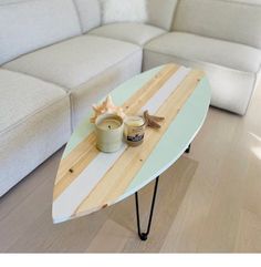 a surfboard shaped table sitting on top of a wooden floor next to a couch