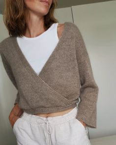 a woman wearing white pants and a brown sweater