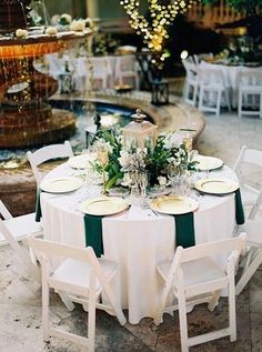 the table is set with white plates and green napkins for an elegant dinner party