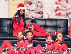 a group of women sitting on top of a couch in matching red pajamas and santa hats