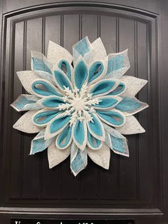 a blue and white paper flower on a black door