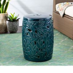 a blue garden stool sitting on top of a rug next to a potted plant