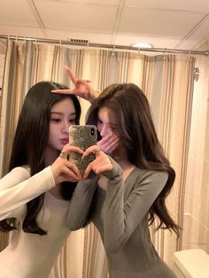 two women are taking a selfie in front of a mirror