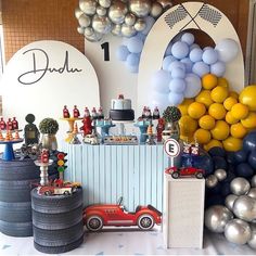 a birthday party with balloons and cars on the table, including an old time car