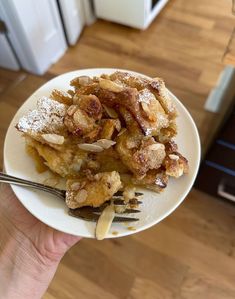 a white plate topped with french toast and powdered sugar on top of it next to a fork