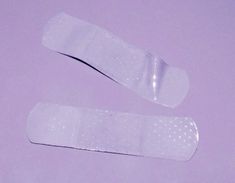 two bandages laying on top of each other in front of a purple background with white dots