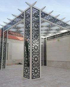 an intricately designed pergolated structure in the middle of a courtyard with tiled flooring