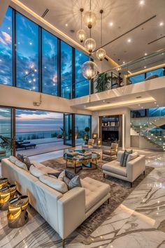 a large living room with high ceilings and floor to ceiling windows that overlook the ocean