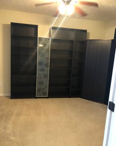 empty room with black bookcases and ceiling fan