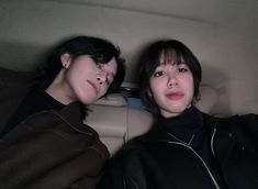 two people sitting in the back seat of a car, one with her eyes closed