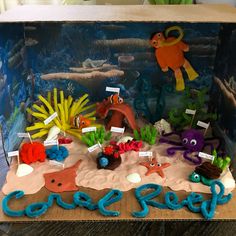 an under the sea themed birthday cake is displayed in a box with corals and other marine creatures