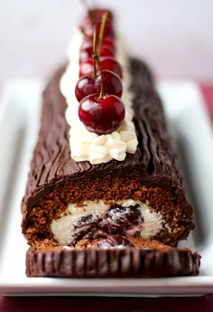 a piece of chocolate cake with cherries on top and the words black forest swiss roll