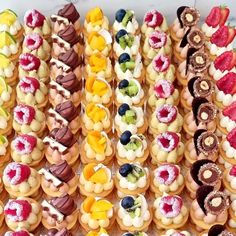 many different types of pastries are arranged on a table with white frosting and colorful toppings