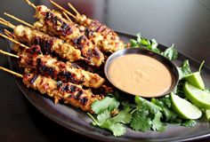 grilled chicken skewers with dipping sauce on the side and garnished with cilantro