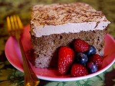 a close up of a piece of cake on a plate with strawberries and blueberries