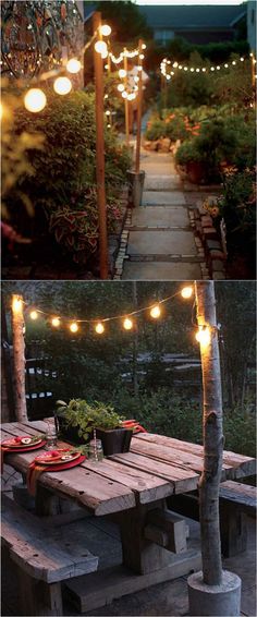 an outdoor dining area with lights strung from the ceiling and wooden benches in the middle