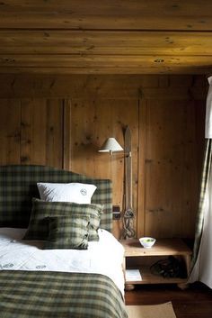 a bedroom with wood paneling and plaid bedding