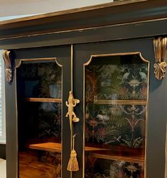 an ornate armoire with gold trim and tassels on the handles, painted black