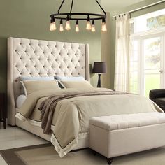 a bedroom with a large bed, chair and ottoman in grey fabric on the floor