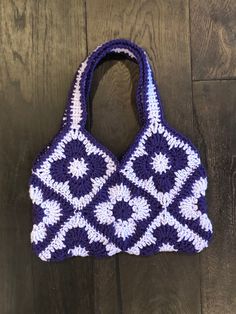 a purple and white crocheted bag sitting on top of a wooden floor