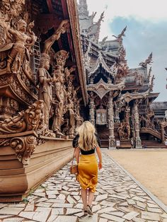 a woman walking down a cobblestone street past an elaborately carved building