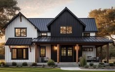 a black and white house with lots of windows on the front porch, covered in metal roofing