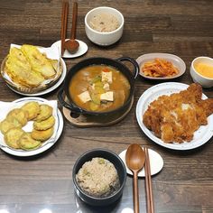 a table topped with plates and bowls filled with different types of food next to chopsticks