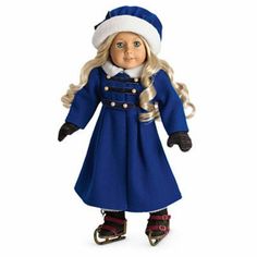 a doll with long blonde hair wearing a blue coat and hat, standing in front of a white background