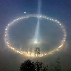 an image of a ring of light in the sky with trees and fog around it