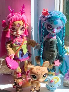 two dolls are standing next to each other in front of a window with pink and blue hair