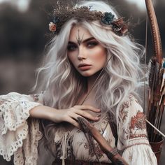 a woman with long white hair holding a bow and arrow in her hand while wearing an elaborate headdress