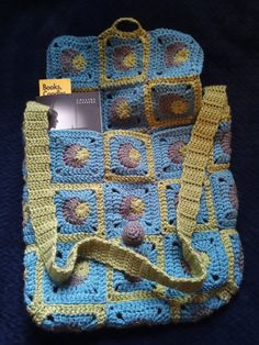 a crocheted bag is sitting on a blue surface with a yellow strap around it