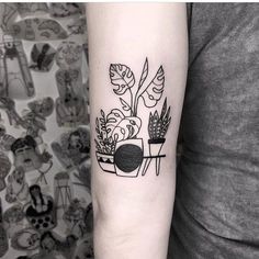 a woman's arm with a black and white plant tattoo on the left forearm