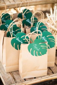 paper bags with green leaves on them are sitting on a wooden table in front of some baskets