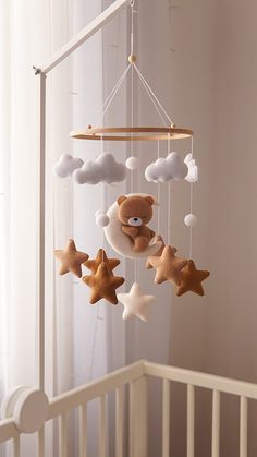 a baby crib with a teddy bear and stars hanging from it