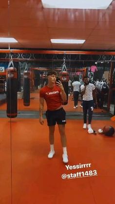 a man standing in a boxing ring talking on a cell phone with other people behind him