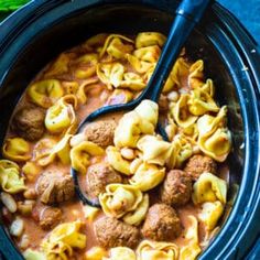 a crock pot filled with pasta and meatballs in tomato sauce, ready to be eaten