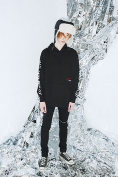 a man standing in front of a pile of tin foil wearing a black hoodie