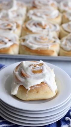 cinnamon rolls with icing sitting on top of white plates