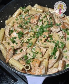 a skillet filled with pasta and chicken covered in sauce, parsley on the side