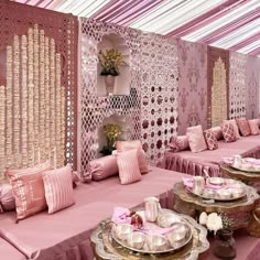 a room filled with lots of pink couches covered in pillows and plates on top of them