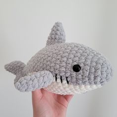 a crocheted stuffed shark is held up to the camera