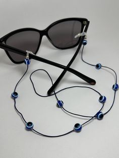 ★ Youthfully flattering evil eye chain ★ Lightweight, not cumbersome, and soft around the neck  ★ Glass eye beads on a navy blue cord ★ To store, just close the arms and wrap your cord around the bridge area ★ Black or white grips - Free extra grips  ★ Approx length - 28 inches/ 70cm Handmade Adjustable Blue Glasses Chains, Handmade Blue Glass Glasses Chains, Trendy Blue Glass Glasses Chains, Trendy Adjustable Blue Glasses Chain, Trendy Blue Glasses Chains As Gift, Handmade Blue Glasses Chains For Festivals, Festival Blue Handmade Glasses Chains, Eye Glass Chain, Beaded Glasses Chain