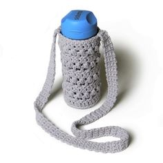 a gray crocheted water bottle with a blue lid on a white background,