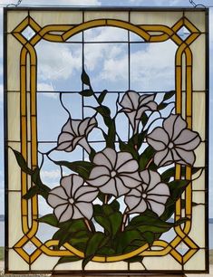 a stained glass window with white flowers in the center and green leaves on the outside