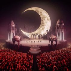 the stage is lit up with red lights and people in front of it, as well as a large moon