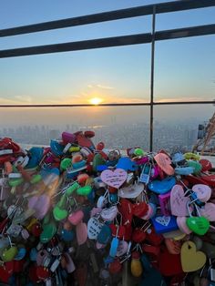 the sun is setting over the city and there are lots of love locks attached to the fence