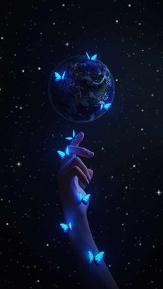 a hand reaching out to touch the earth with butterflies flying around it on a night sky background