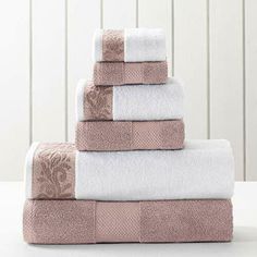 towels stacked on top of each other in front of a white wall with wood paneling