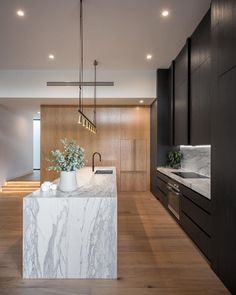 a kitchen with marble counter tops and wooden cabinets, along with stairs leading up to the second floor